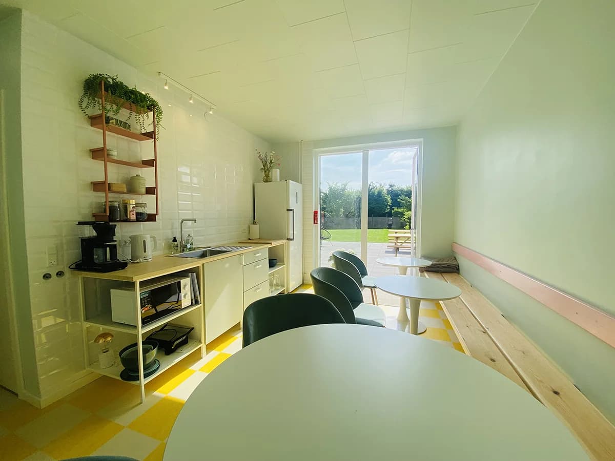 Die Gemeinschaftsküche mit Esstischen und Blick in den Garten
