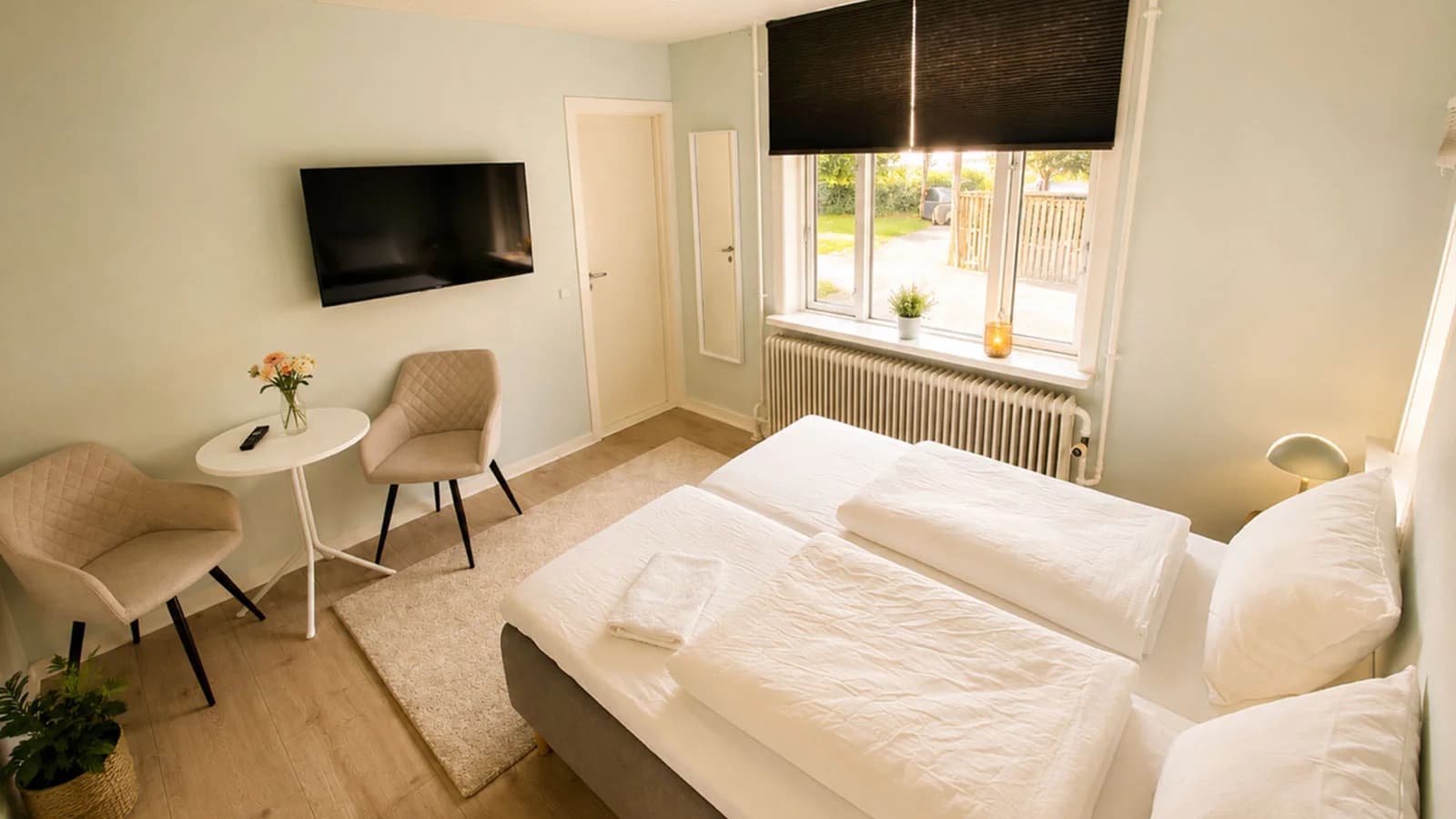 Helles Doppelzimmer im grünen Haus mit Fernseher und Sessel