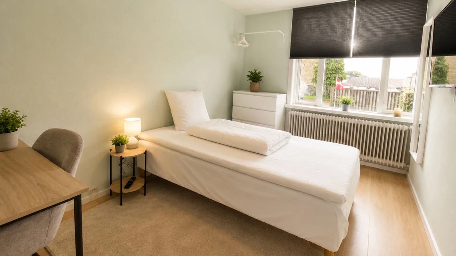 Einzelzimmer mit Bett, Kommode und Sessel