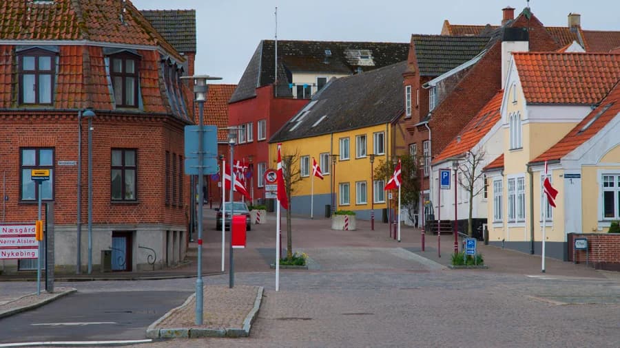 Eine Straße in der Altstadt von Stubbekøbing mit roten und gelben Häusern und Fahnen